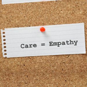 A bulletin board with a piece of paper pinned to it. The paper says Care = Empathy